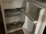 a small white refrigerator in the corner of a room