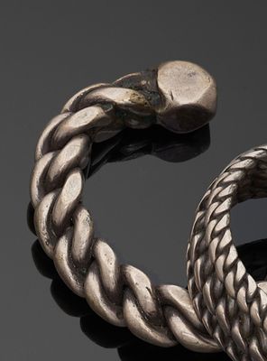 deux bracelets en argent posés sur une surface noire, sur fond noir