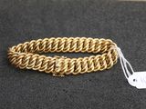 gros plan d'un bracelet en chaîne en or sur une surface noire