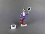 une figurine représentant un homme en costume violet, tenant un chapeau et une valise