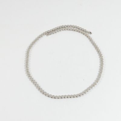 un gros plan d'un bracelet en perles argentées posé sur une surface blanche