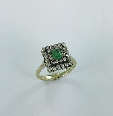 a close up of a ring with a green stone surrounded by white diamonds