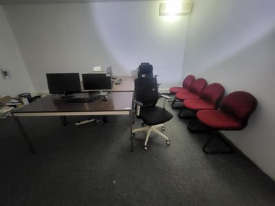 une pièce équipée d'un bureau, de chaises et d'un ordinateur posé dessus