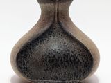 un vase noir et blanc posé sur une surface blanche