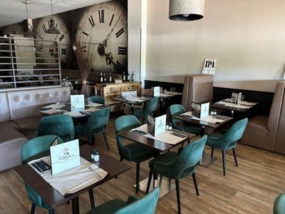 des tables et des chaises dans un restaurant où est accrochée une grande horloge au mur