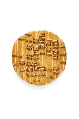 a wooden plate with gold beads on it on a white surface