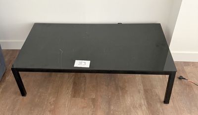 une table basse noire sur laquelle est posée une étiquette blanche