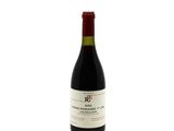 the bottle of red wine is sitting on a white surface
