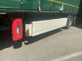 a green semi truck with a red tail light on it