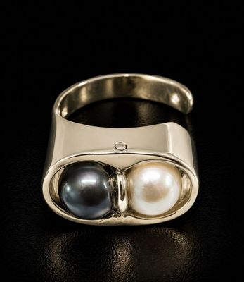 a close up of a ring with two pearls on it