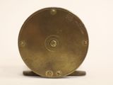 a small brass clock on a stand on a white surface