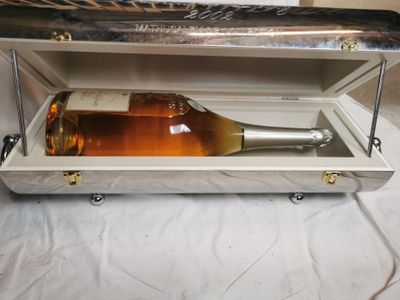 une bouteille de vin dans un coffret en argent, posée sur une table