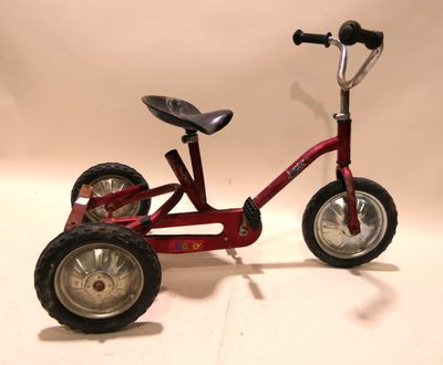 a red tricycle with a black seat and a black seat