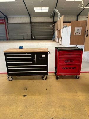 two red and black tool boxes sitting on top of a wooden table