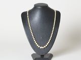 un collier de perles blanches sur un mannequin noir