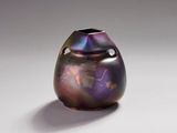 un vase violet posé sur une surface blanche