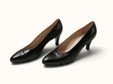 Les chaussures noires de la femme reposent sur une surface blanche.
