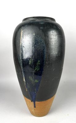 un vase noir posé sur une table, sur fond blanc