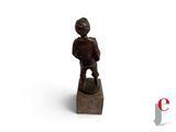 une petite statue représentant un garçon debout sur un bloc