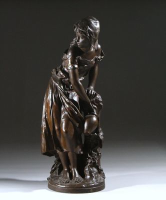an antique bronze statue of a woman sitting on a rock