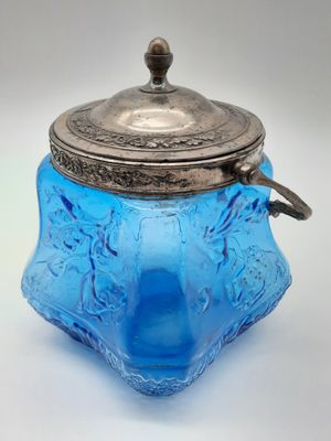bocal en verre bleu avec un couvercle argenté sur fond blanc