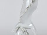 une image représentant une statue d'oiseau blanc posée sur un socle en bois