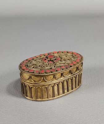 une image représentant une boîte dorée et rouge posée sur une table