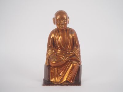 statue d'un moine assis sur un tabouret, sur fond blanc