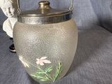 a glass vase with flowers painted on it sitting on a blue cloth