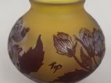 a yellow vase with purple flowers on it on a white surface