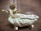 a figurine of an angel sitting in a bathtub