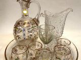 des bouteilles et des verres posés sur un plateau, sur lequel trône un pichet en verre