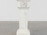 un socle en marbre blanc surmonté d'une horloge
