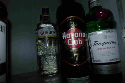 Des bouteilles d'alcool sont alignées sur une étagère dans une pièce sombre