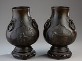pair of bronze vases sitting on top of a table