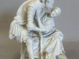 a white statue of a man and a woman sitting on a bench