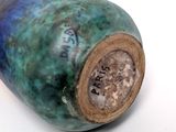 a blue and green vase sitting on a white surface