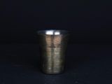 Gros plan sur une tasse en métal posée sur une surface noire