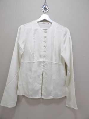 the white shirt is hanging on a hanger on the wall