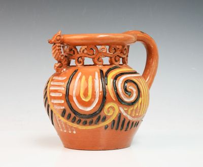 an orange vase with a black and white design on it