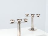un ensemble de cinq bougeoirs en argent posés sur une table blanche