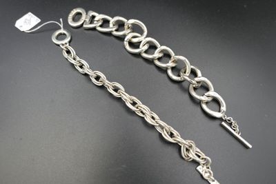 un gros plan sur une paire de bracelets à chaîne en argent posés sur une surface noire