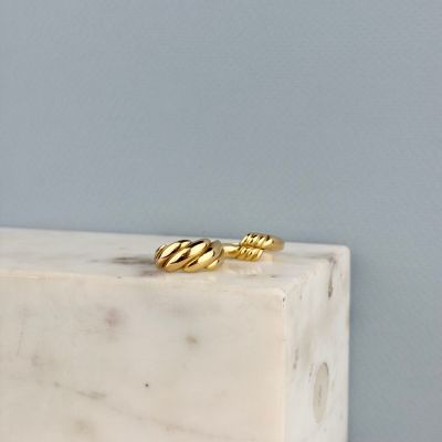 un gros plan d'une bague en or posée sur un bloc de marbre