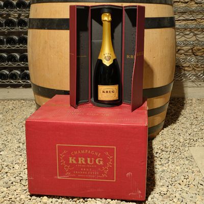 a bottle of wine in a red box in front of a wine barrel