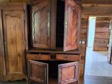 une armoire en bois à deux portes, ouverte, au milieu d'une pièce