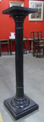 un socle noir sur lequel est posée une horloge, dans une pièce