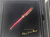 a red pen sitting in a black box with a gold writing on it