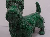 a small green dog figurine on a white surface