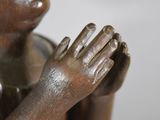 a bronze statue of a woman holding her hands together