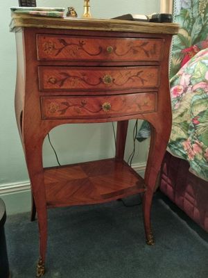 a small table with a lamp on top of it next to a bed